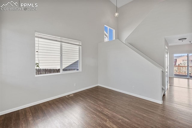 unfurnished living room featuring dark wood-type flooring and a high ceiling