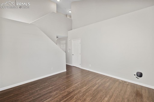 unfurnished room featuring a high ceiling and dark hardwood / wood-style flooring