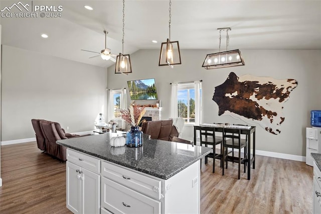 kitchen featuring dark stone countertops, white cabinets, light hardwood / wood-style flooring, and vaulted ceiling