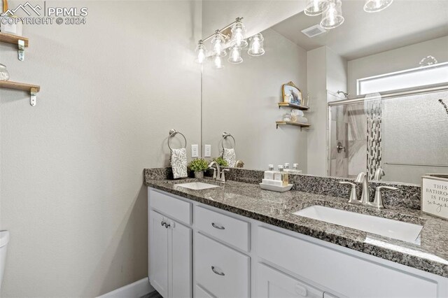 bathroom featuring toilet, vanity, and a shower with shower door