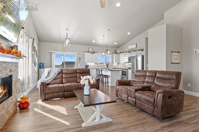 living room with a fireplace, high vaulted ceiling, and light hardwood / wood-style flooring