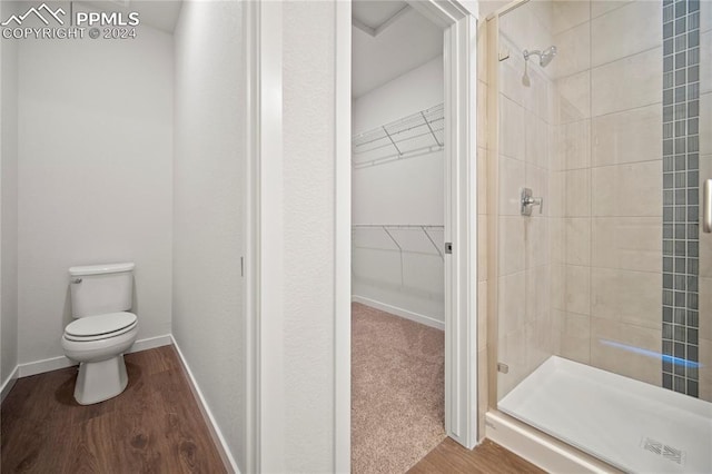 bathroom featuring hardwood / wood-style flooring, a shower with shower door, and toilet