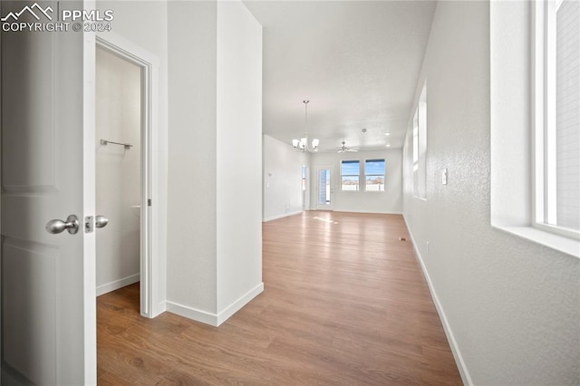 hallway featuring light hardwood / wood-style flooring and a chandelier