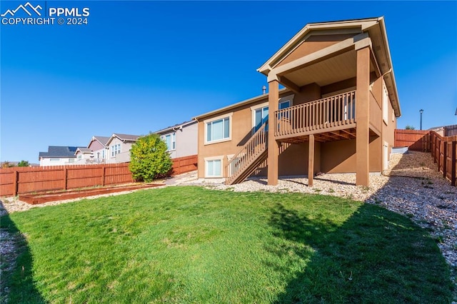 back of property with a wooden deck and a yard