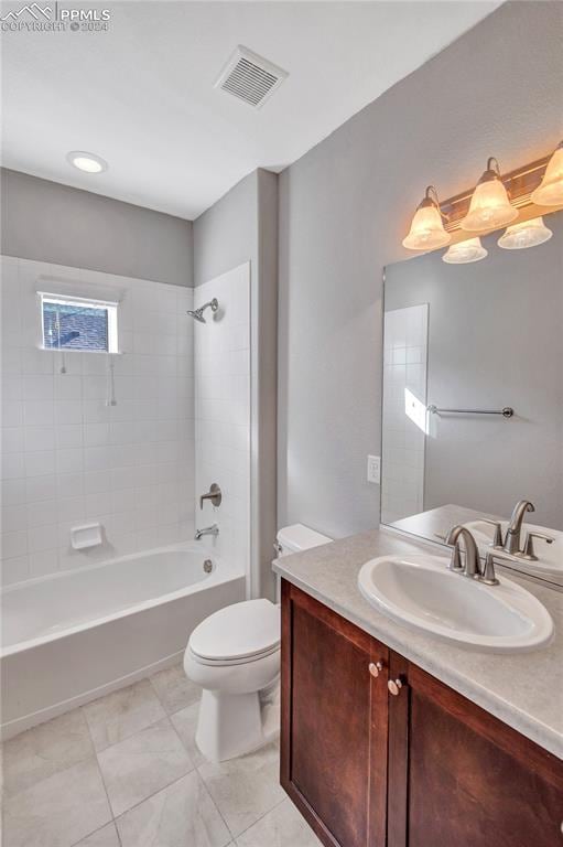 full bathroom with tiled shower / bath, vanity, and toilet