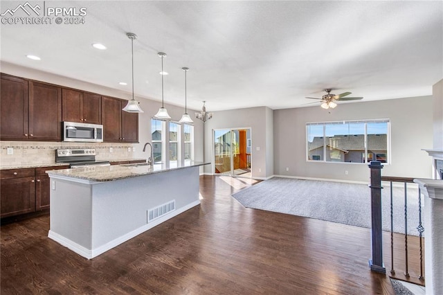 kitchen featuring tasteful backsplash, dark hardwood / wood-style flooring, decorative light fixtures, stainless steel appliances, and an island with sink