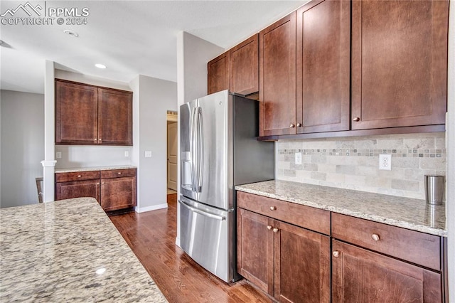 kitchen featuring tasteful backsplash, light stone countertops, dark hardwood / wood-style floors, and stainless steel refrigerator with ice dispenser