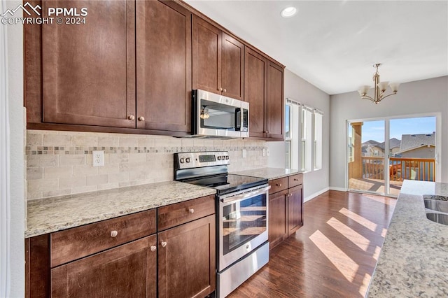 kitchen with appliances with stainless steel finishes, light stone counters, an inviting chandelier, and dark hardwood / wood-style flooring