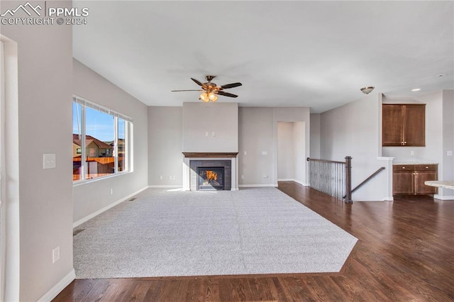 unfurnished living room with ceiling fan, a tile fireplace, and dark hardwood / wood-style floors