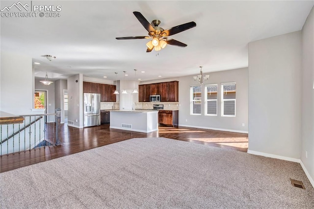 unfurnished living room with ceiling fan with notable chandelier and dark hardwood / wood-style flooring