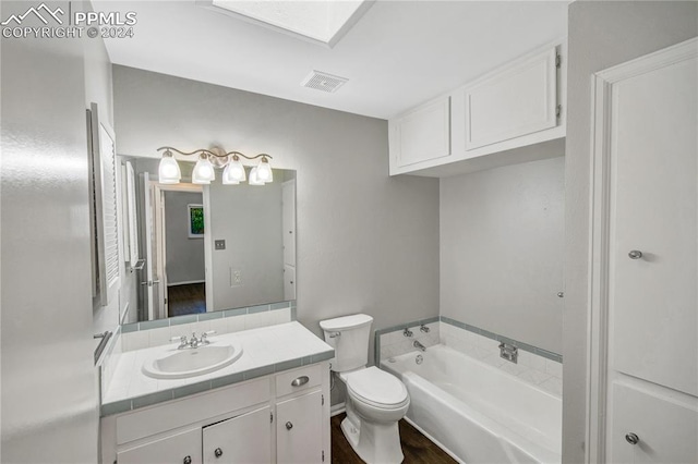 bathroom with wood-type flooring, a skylight, vanity, toilet, and a bathtub