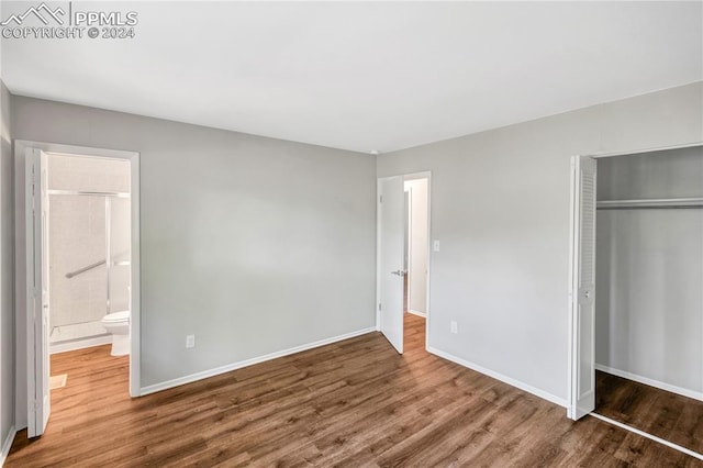 unfurnished bedroom featuring connected bathroom, a closet, and wood-type flooring