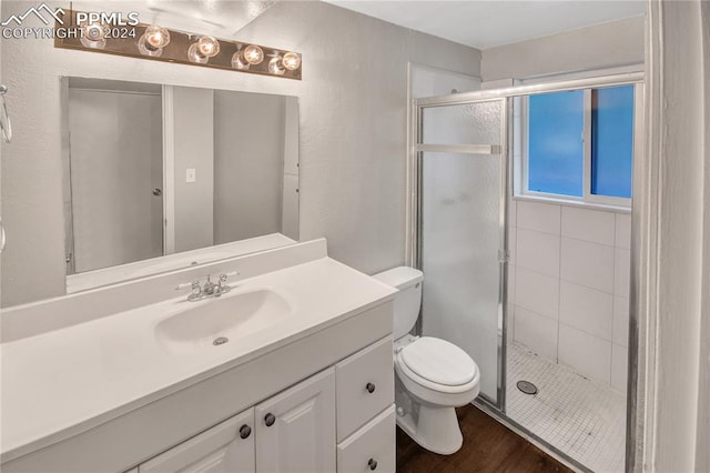 bathroom featuring vanity, hardwood / wood-style floors, a shower with shower door, and toilet