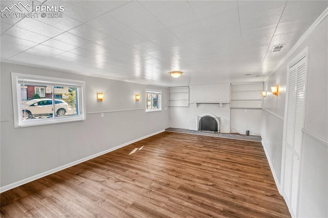 unfurnished living room featuring hardwood / wood-style floors, crown molding, and a fireplace