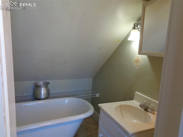 bathroom with lofted ceiling, a tub to relax in, tile patterned flooring, and vanity