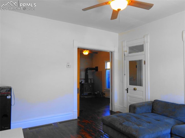 living room with ceiling fan, dark hardwood / wood-style floors, and a wood stove