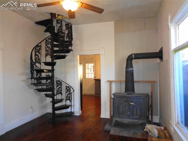 living room featuring ceiling fan, dark hardwood / wood-style flooring, and a wood stove