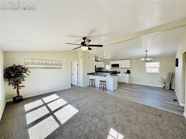 unfurnished living room with a textured ceiling, ceiling fan with notable chandelier, vaulted ceiling, and hardwood / wood-style floors