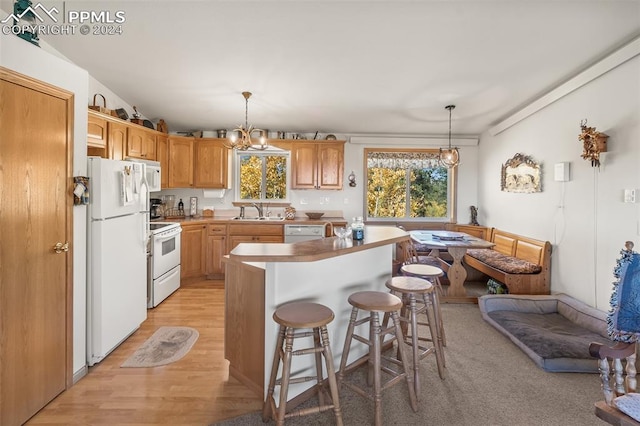 kitchen featuring an inviting chandelier, hanging light fixtures, light hardwood / wood-style floors, and white appliances