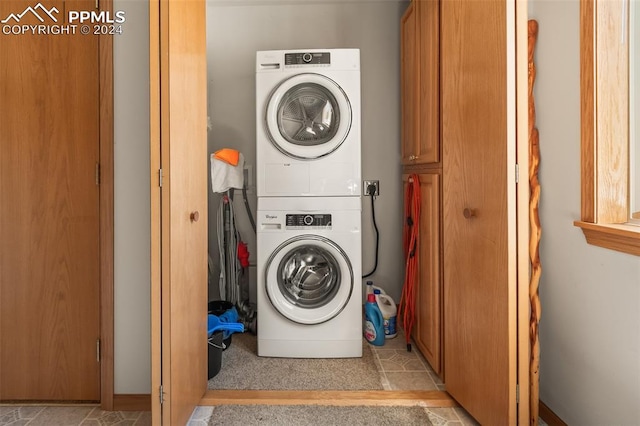 washroom featuring stacked washer / drying machine and light tile patterned floors