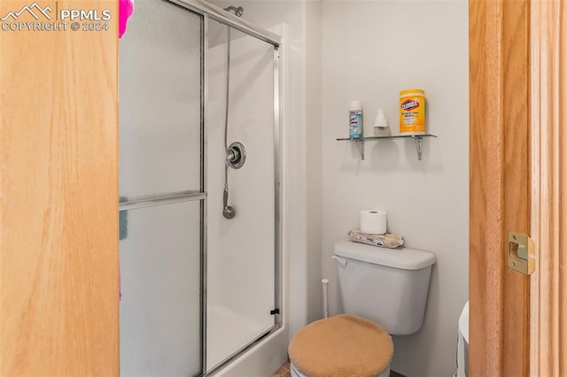 bathroom with toilet and a shower with shower door