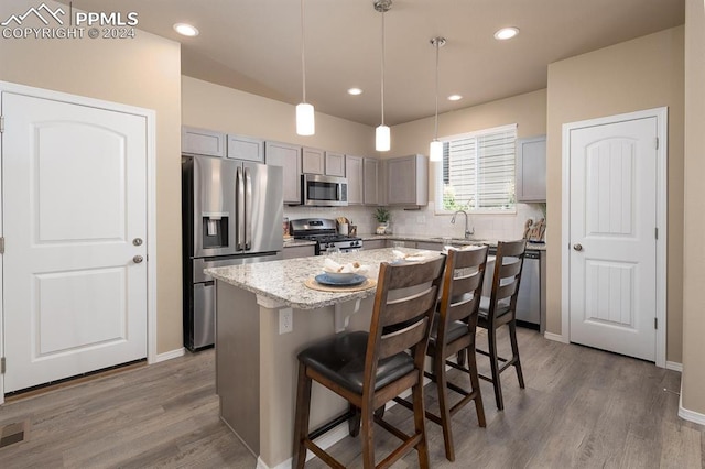 kitchen featuring light stone counters, a kitchen island, dark wood-type flooring, gray cabinets, and stainless steel appliances