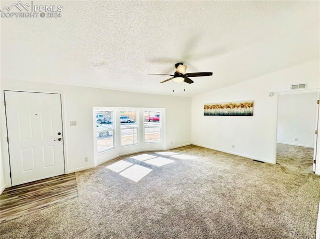 unfurnished living room with ceiling fan, a textured ceiling, carpet floors, and vaulted ceiling