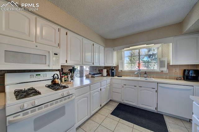 kitchen featuring decorative backsplash, white cabinets, light tile patterned flooring, sink, and white appliances