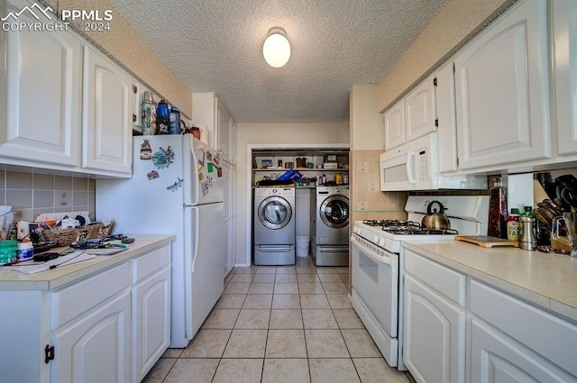 kitchen with white appliances, washer and clothes dryer, white cabinets, decorative backsplash, and light tile patterned floors