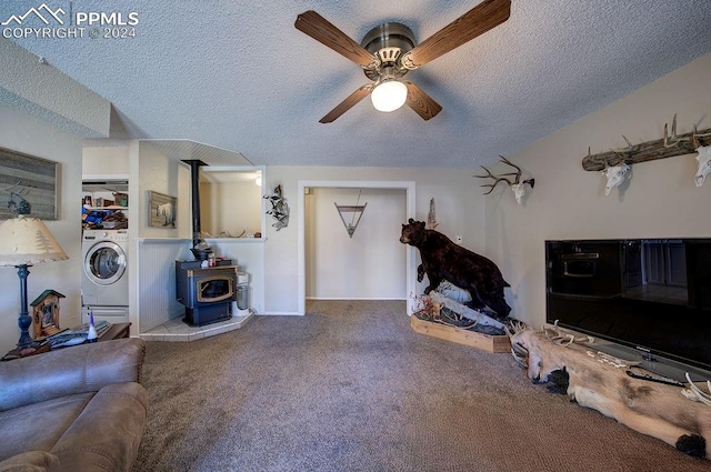 carpeted living room featuring washer / dryer, a wood stove, a textured ceiling, and ceiling fan