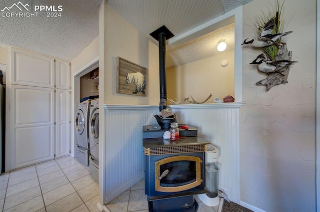 laundry area with a textured ceiling, light tile patterned flooring, and washer and clothes dryer