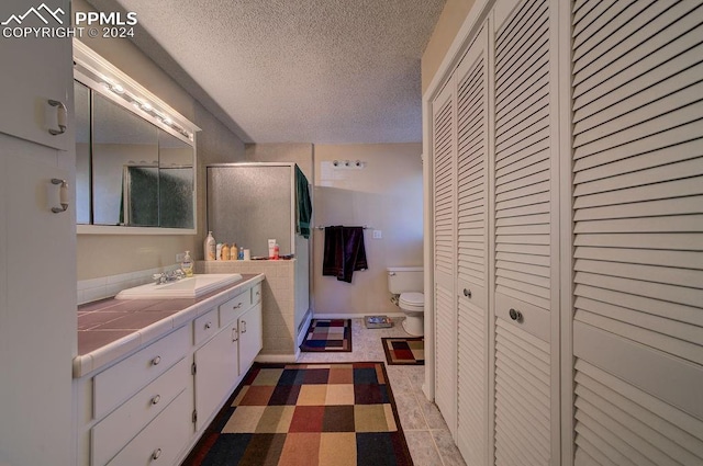 bathroom featuring a textured ceiling, walk in shower, toilet, vanity, and tile patterned floors