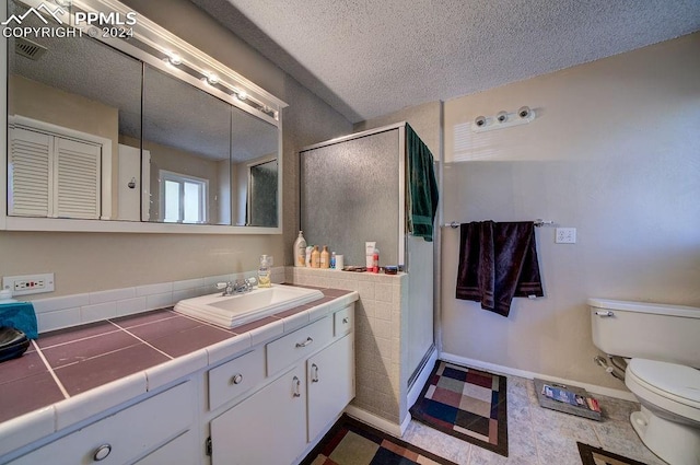 bathroom with a textured ceiling, an enclosed shower, toilet, tile patterned floors, and vanity