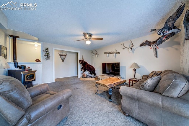 living room featuring carpet flooring, a wood stove, a textured ceiling, and ceiling fan