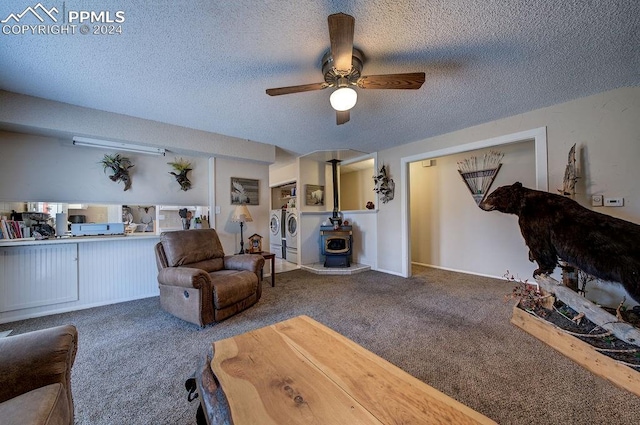 living room with a wood stove, washer and dryer, carpet flooring, and ceiling fan