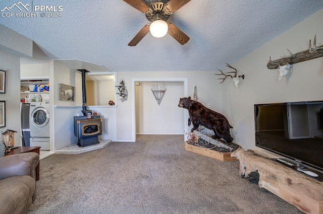 carpeted living room featuring a wood stove, a textured ceiling, independent washer and dryer, and ceiling fan