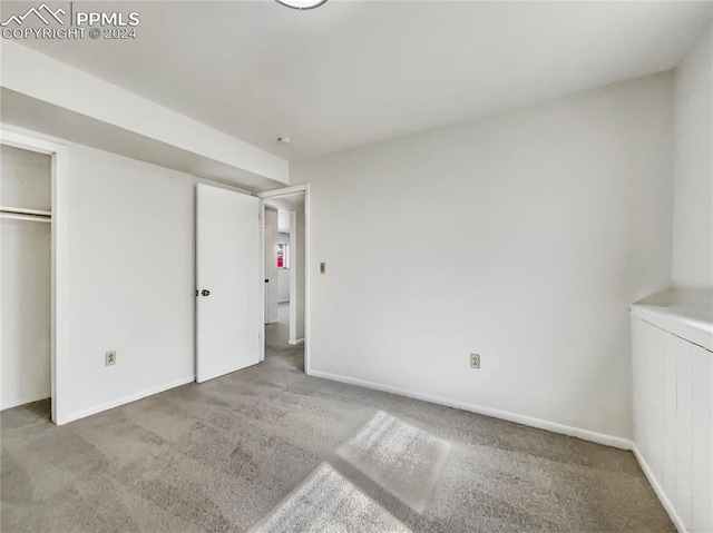 unfurnished bedroom with light carpet and a closet