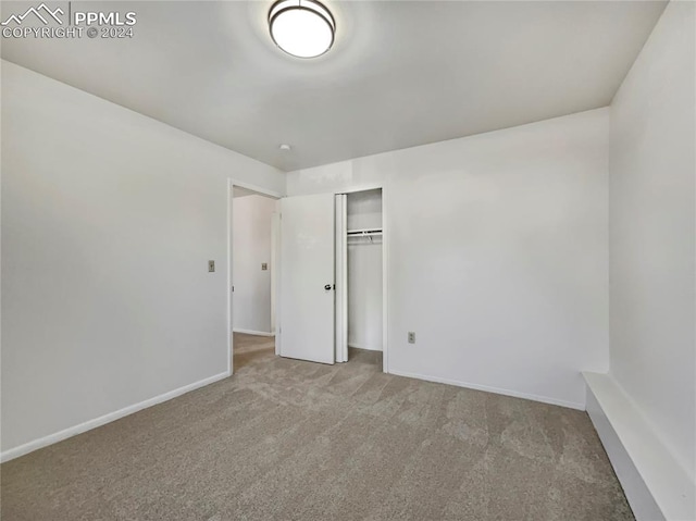 unfurnished bedroom featuring light carpet and a closet