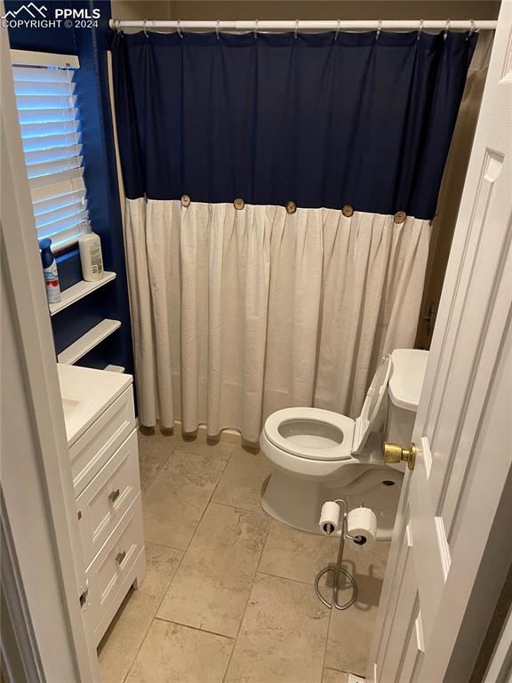 bathroom with walk in shower, vanity, and toilet