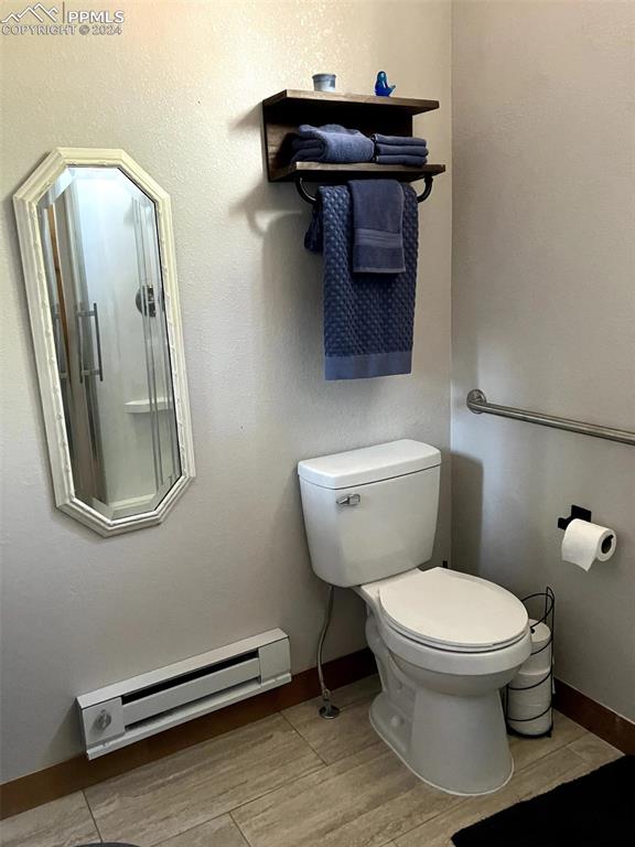 bathroom with hardwood / wood-style floors, toilet, and a baseboard heating unit