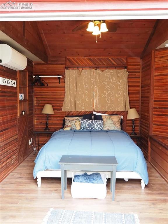 bedroom with wood ceiling, wood walls, light hardwood / wood-style floors, and a wall unit AC