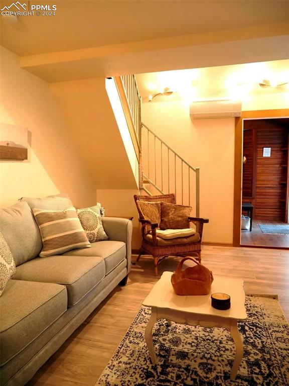 living room featuring wood-type flooring and a wall unit AC