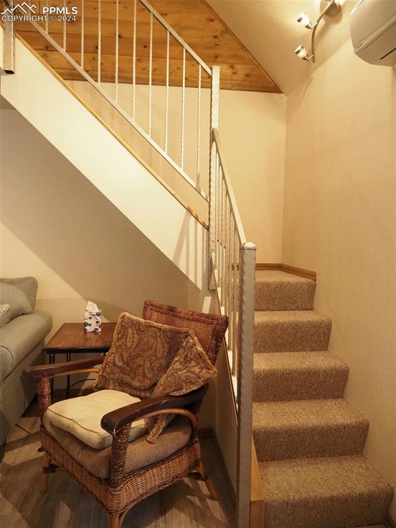 staircase with wood-type flooring and a wall mounted air conditioner