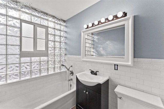 bathroom with vanity, a bathtub, toilet, and tile walls