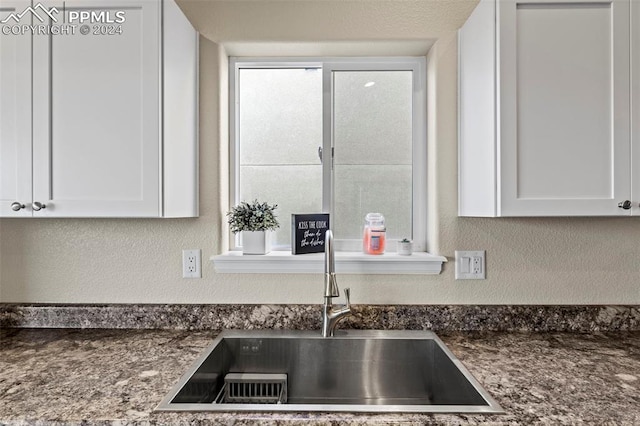 kitchen featuring dark stone countertops, sink, and white cabinetry