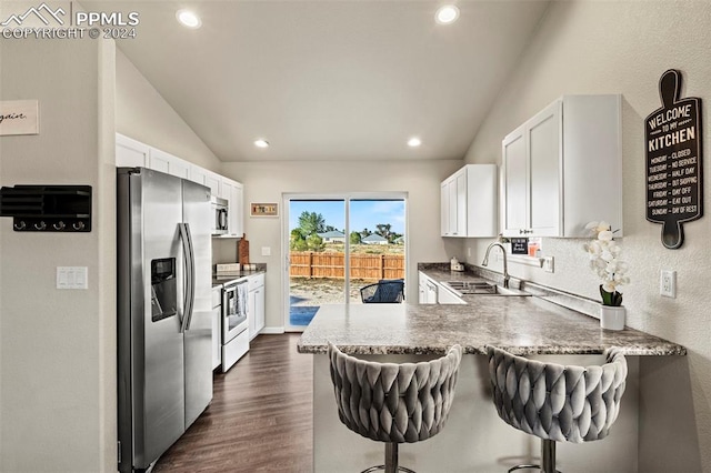 kitchen featuring stainless steel appliances, kitchen peninsula, white cabinets, and vaulted ceiling