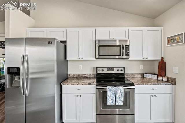 kitchen with lofted ceiling, appliances with stainless steel finishes, and white cabinetry