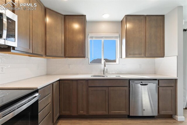 791 Little Bear Grv, Colorado Springs, CO 80907 - kitchen with appliances with stainless steel finishes, a sink, light wood finished floors, light countertops, and backsplash