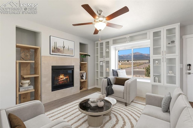 791 Little Bear Grv, Colorado Springs, CO 80907 - living area featuring wood finished floors, a tiled fireplace, ceiling fan, and built in shelves