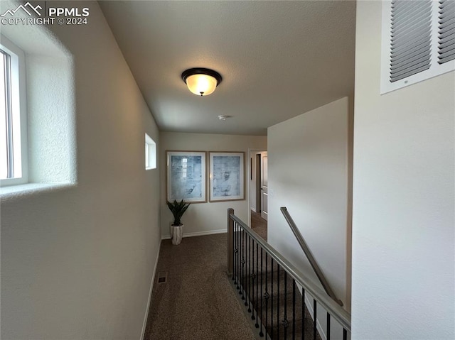 hall with dark carpet and plenty of natural light